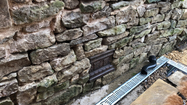 Cast iron grate set into the drystone wall